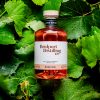 Bottle of Bridport Distilling Co's limited edition Rosé gin laying on a bed of green grape vines